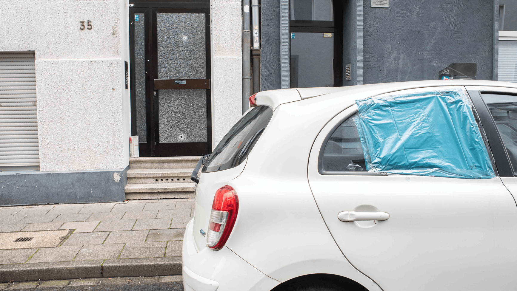 Die Scheibe eines Autos ging zu Bruch, zwei Einschusslöcher sind in der Haustür zu sehen: Der 31-Jährige konnte sich in den Hauseingang retten. Die Scheibe eines Autos ging zu Bruch, zwei Einschusslöcher sind in der Haustür zu sehen: Der 31-Jährige konnte sich in den Hauseingang retten.