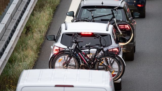 Zwei Fahrzeuge mit Fahrrädern im Gepäck stehen auf einer Autobahn Zwei Fahrzeuge mit Fahrrädern im Gepäck stehen auf einer Autobahn