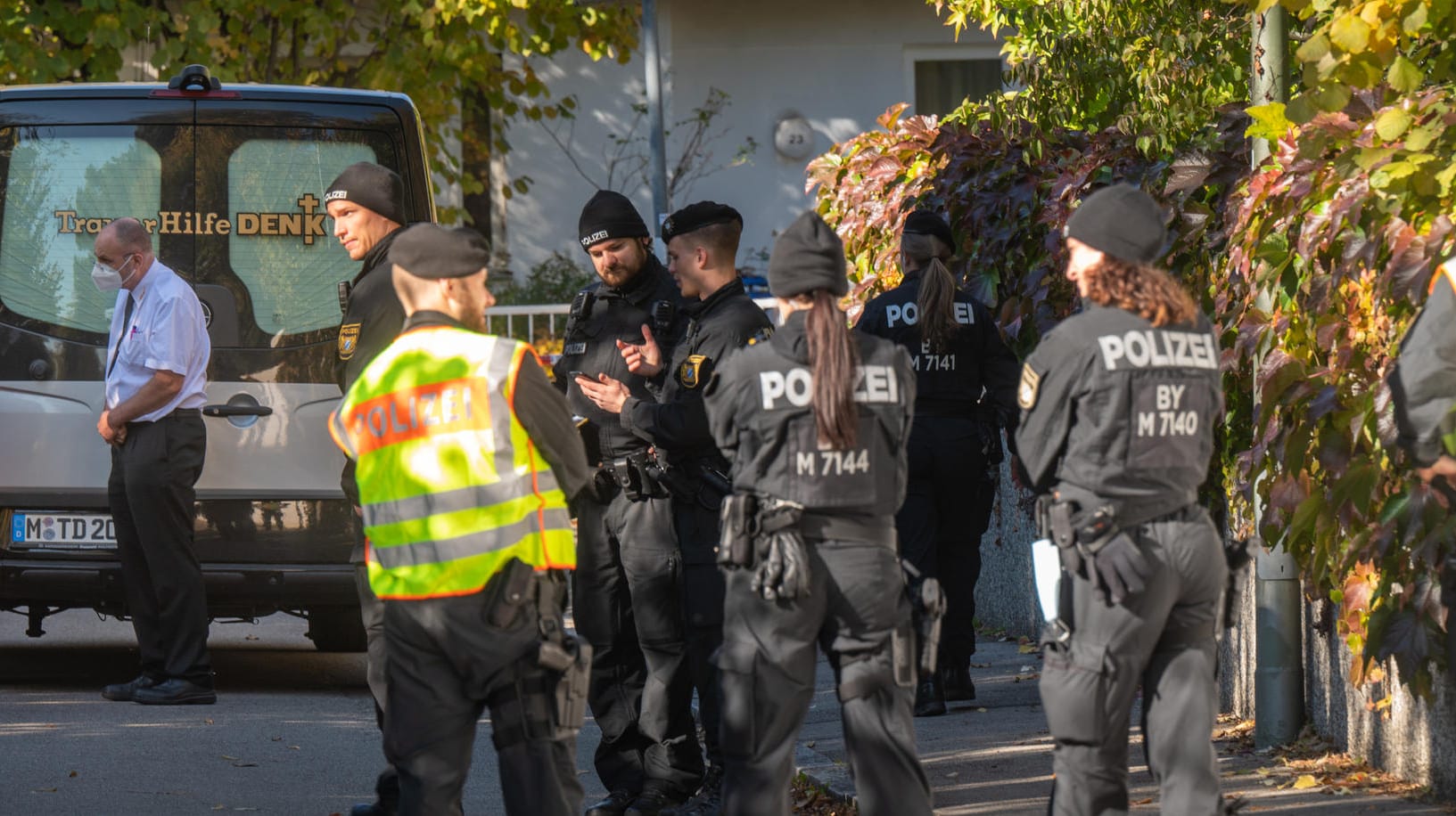 Polizisten und ein Bestatter stehen vor dem Tatort in München, wo eine 14-Jährige tot aufgefunden worden ist: Ein 17-Jähriger gilt als Tatverdächtiger.