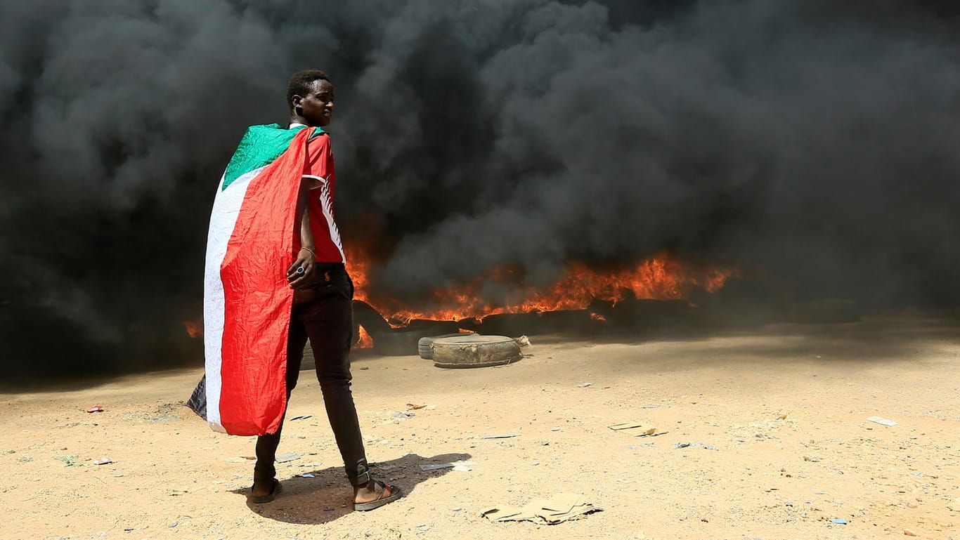 Ein Mann mit einer Sudan-Flagge vor brennenden Reifen: In den vergangenen Tagen protestierten zahlreiche Menschen auch gegen die Aussicht auf eine Militärregierung.