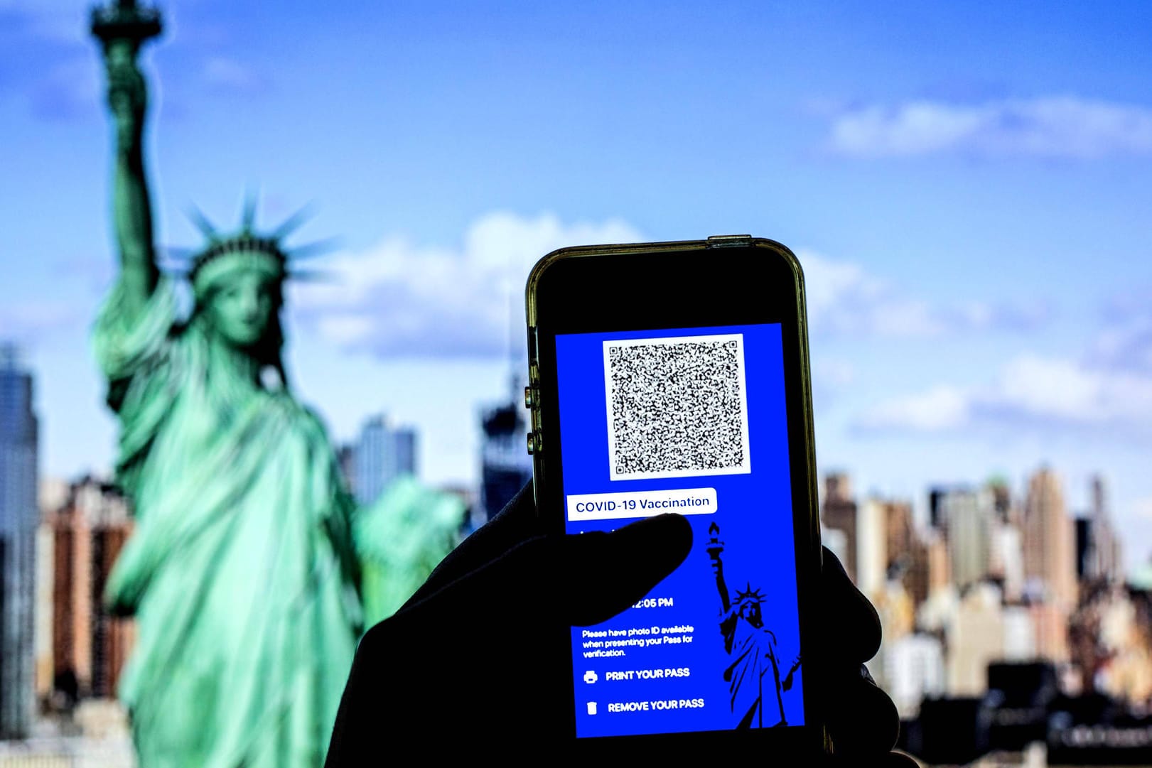 Digitaler Impfpass vor der Freiheitsstatue (Symbolbild): Einreisen in die USA sind ab November nach einer anerkannten Corona-Impfung wieder möglich.