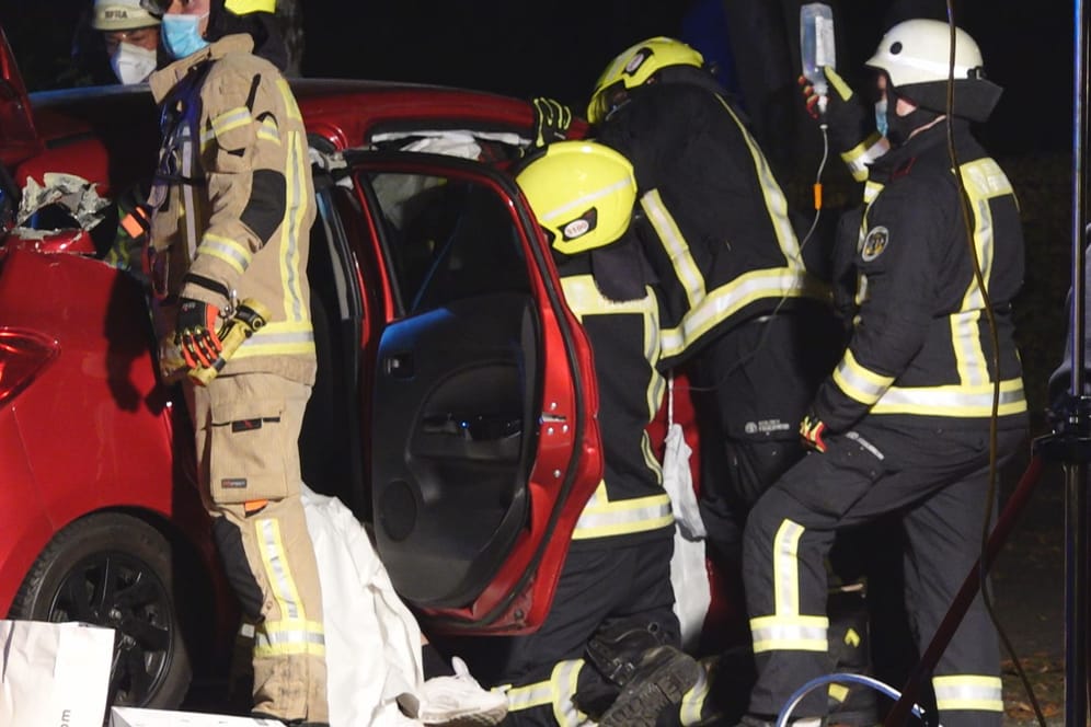 Einsatz in der Nacht: Während im Auto Verletzte versorgt werden, schneiden andere Feuerwehrleute das Dach ab.