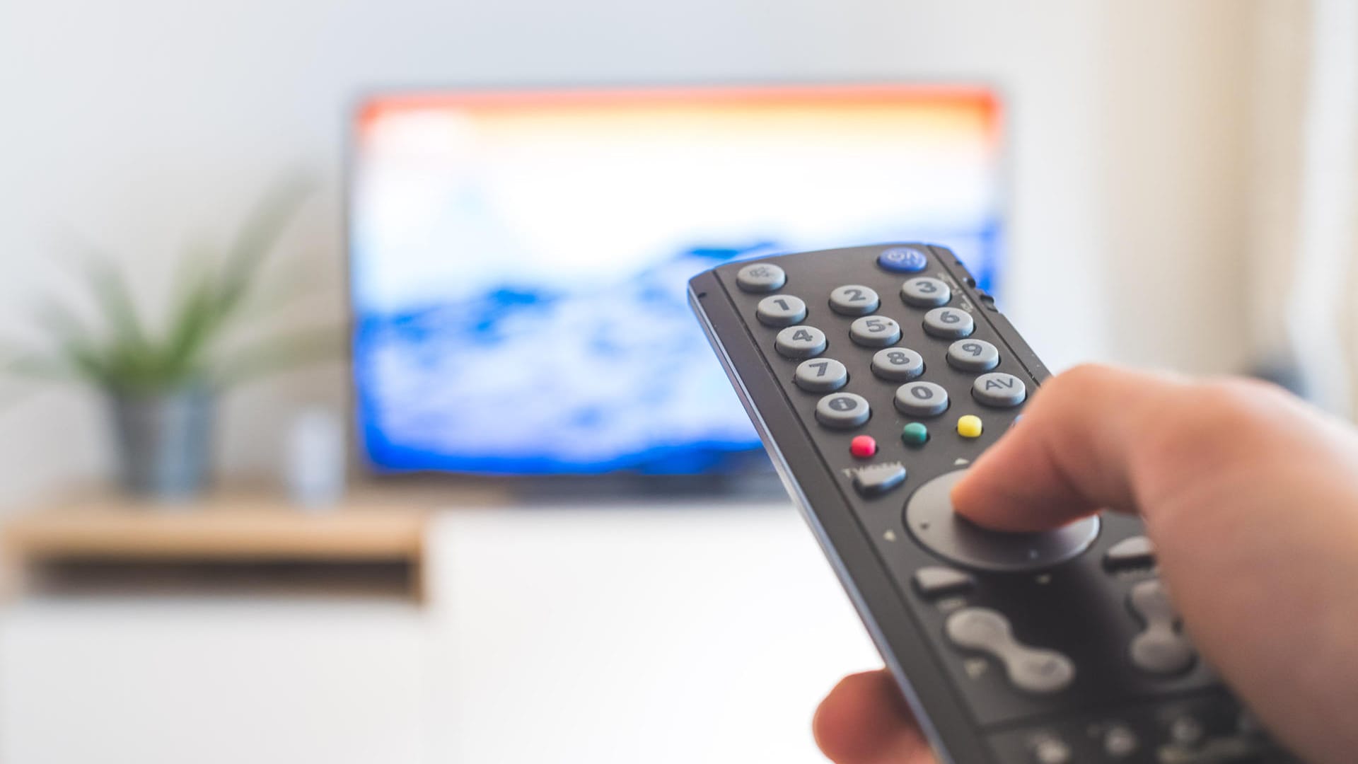 Eine Fernbedienung vor dem Fernseher: Mit einem Sat-Receiver empfangen Sie das TV-Programm.