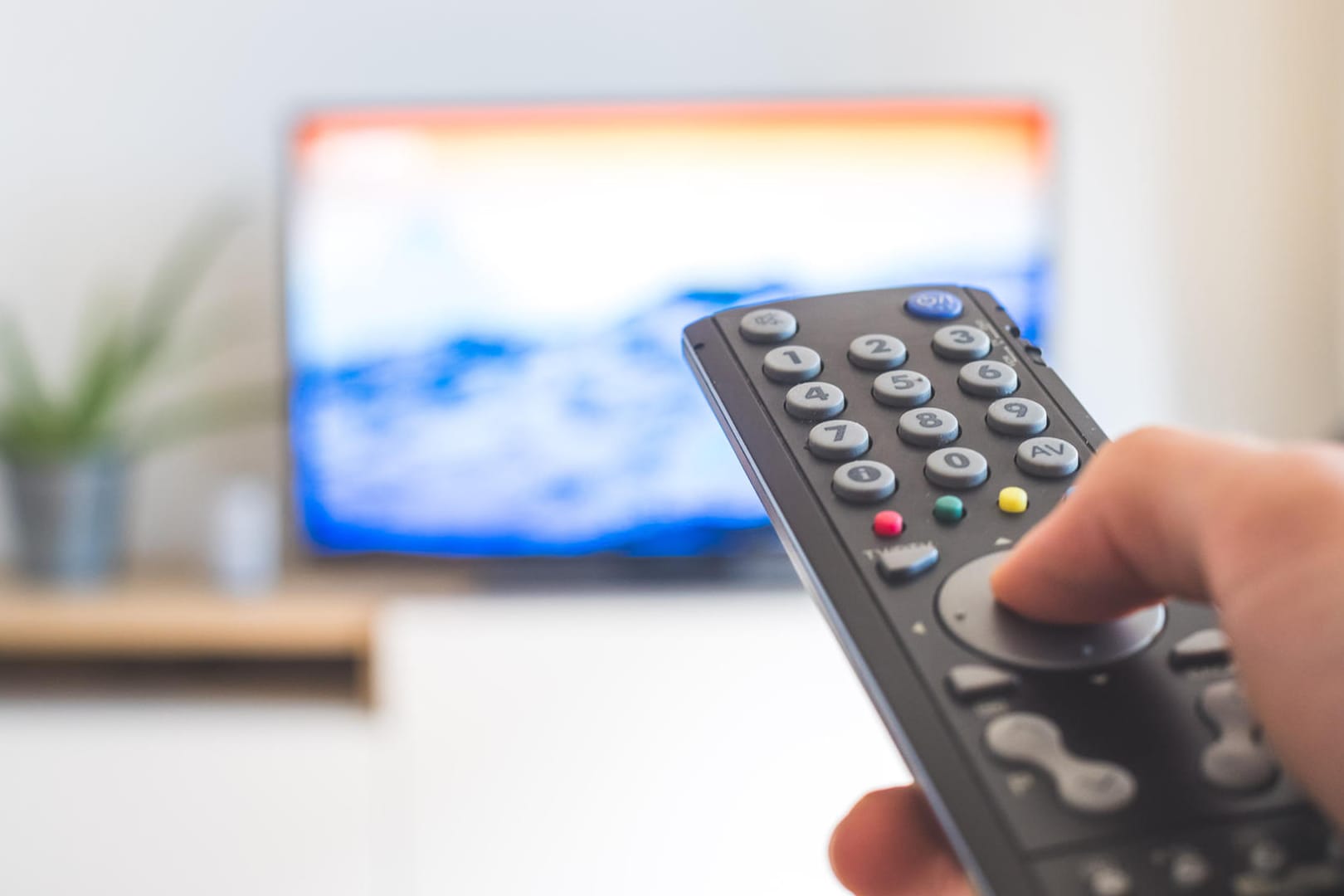 Eine Fernbedienung vor dem Fernseher: Mit einem Sat-Receiver empfangen Sie das TV-Programm.