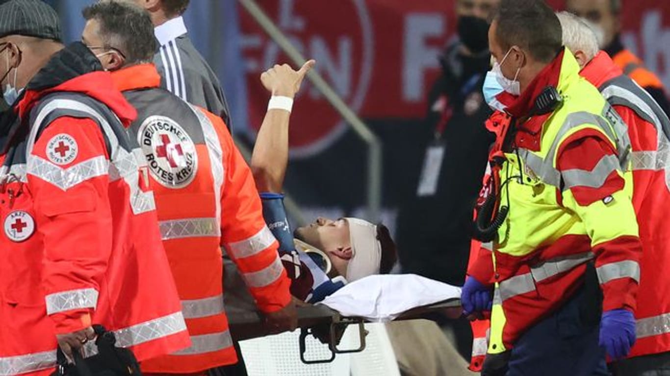 Der Nürnberger Tom Krauß (M) wird verletzt aus dem Stadion getragen, zeigt aber mit dem Daumen nach oben.