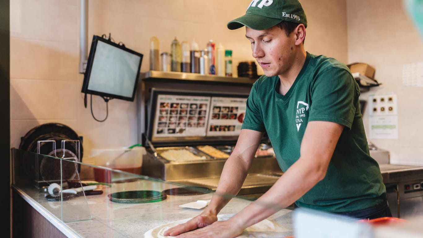 Ein Mitarbeiter bereitet eine Pizza zu: New York Pizza will in Deutschland eine starke Nummer zwei am Mark werden.