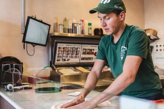 Ein Mitarbeiter bereitet eine Pizza zu: New York Pizza will in Deutschland eine starke Nummer zwei am Mark werden.