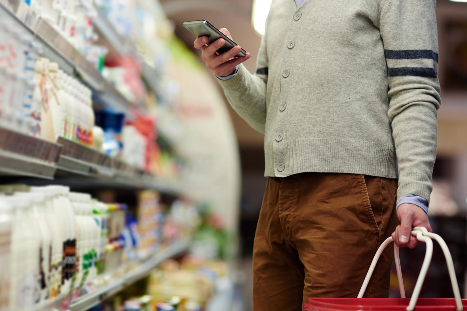 Ein Mann im Supermarkt schaut auf sein Smartphone: Worauf gilt es bei einer Schilddrüsenunterfunktion in puncto Ernährung zu achten?