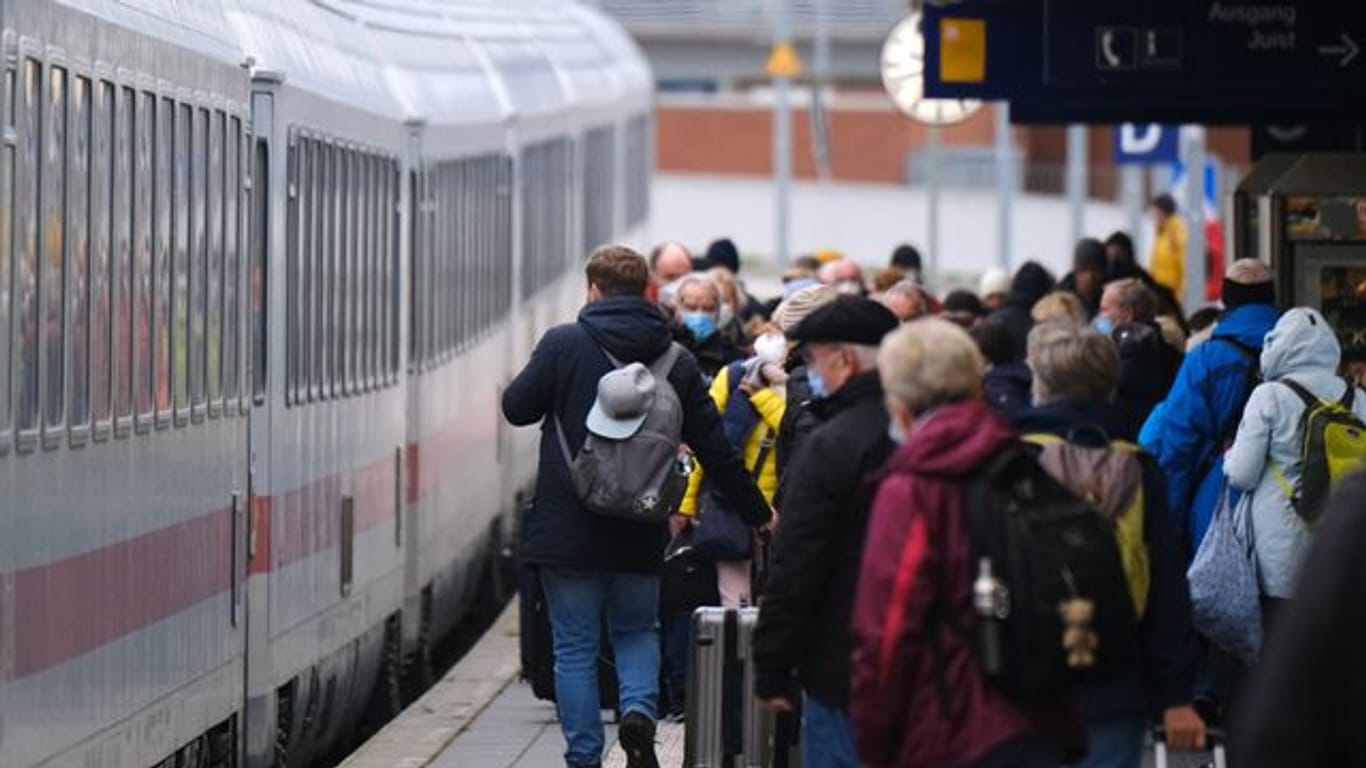 Menschen stehen auf einem Bahnsteig am Bahnhof Norddeich Mole vor einem eingefahrenen Zug (Archivbild): Ob das 49-Euro-Ticket gilt, ist wieder nicht geklärt.