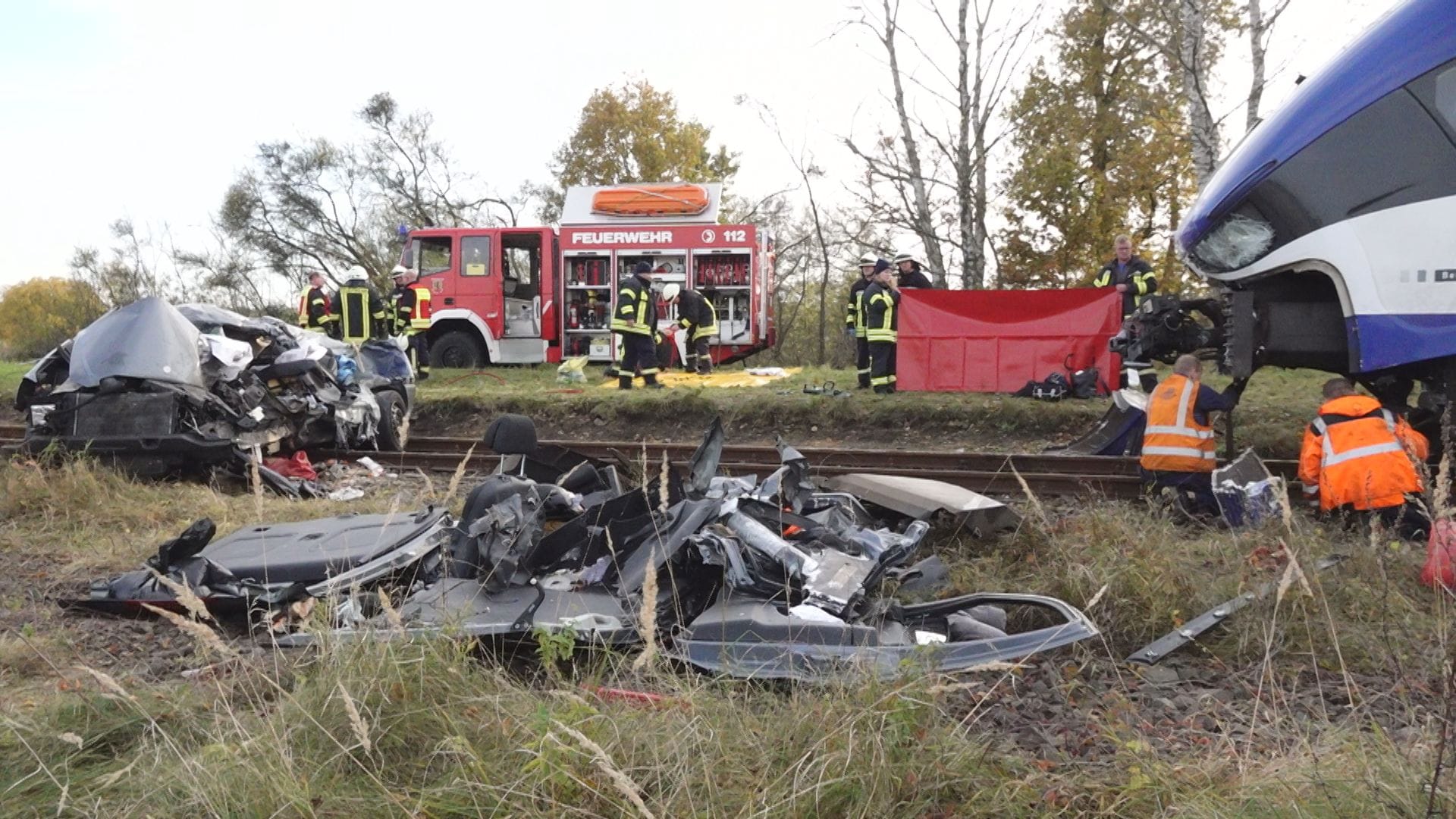 Einsatzkräfte untersuchen die Unfallstelle: Das Auto wurde von der Bahn noch meterweit mitgeschleift.