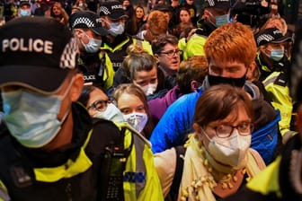 Greta Thunberg (Mitte, mit weißer Maske) musste von Polizeibeamten geschützt werden, als sie die Bahnstation in Glasgow erreichte.