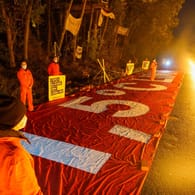 Protestanten in Lützerath: Mit einem roten Banner und einer "Feuerlinie" demonstriert Greenpeace vor einem Bauernhof in Lützerath gegen den Braunkohletagebau Garzweiler.