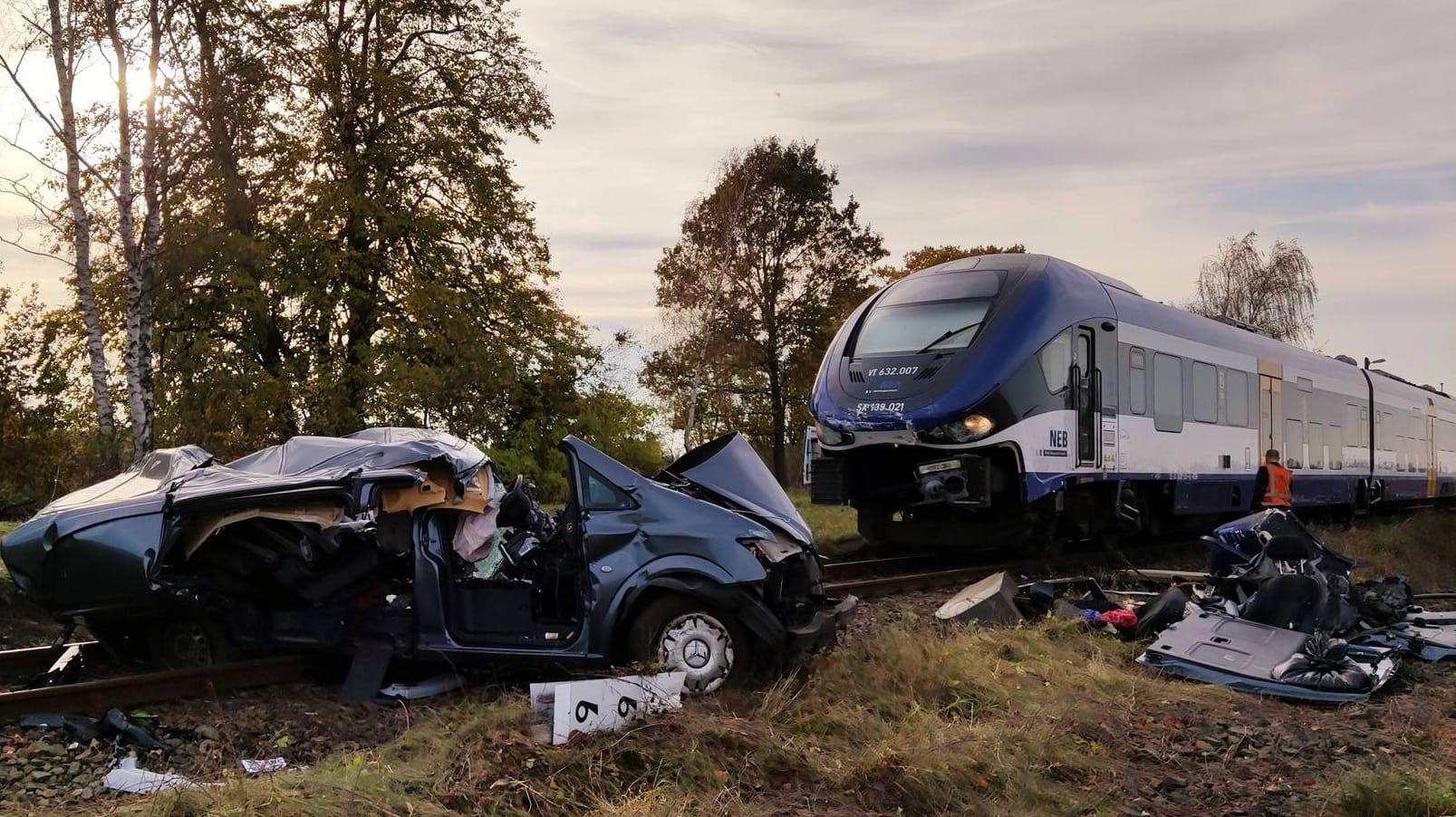 Ein zerstörter Transporter liegt auf Bahngleisen vor einem Zug: Bei dem Unfall in Brandenburg sind zwei Menschen ums Leben gekommen.