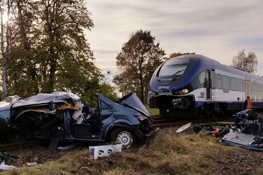Ein zerstörter Transporter liegt auf Bahngleisen vor einem Zug: Bei dem Unfall in Brandenburg sind zwei Menschen ums Leben gekommen.