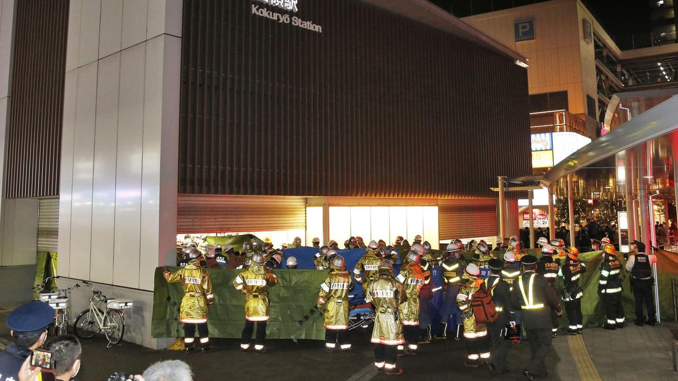 Feuerwehrleute versammeln sich am Bahnhof Kokuryo: In einem Zug hat ein Mann mehrere Menschen attackiert und Feuer gelegt.
