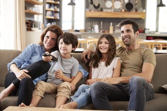 Eine Familie sitzt vor dem Fernseher (Symbolbild): Die Mediennutzung der Deutschen ist auf einen Rekordwert gestiegen.