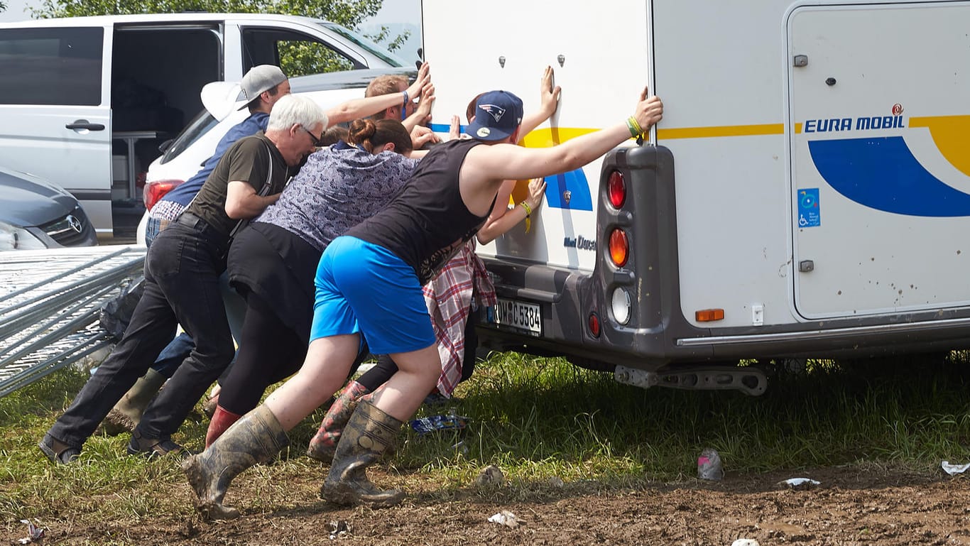 Festivalbesucher schieben am 05. Juni ein Wohnmobil vom schlammigen "Rock am Ring"-Gelände.