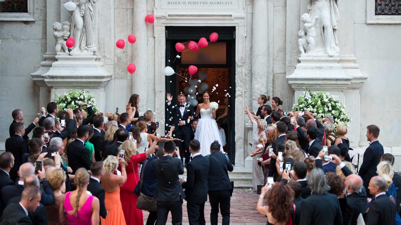 Jede Menge Gäste, Fotografen und Luftballons begrüßen das Paar nach der Hochzeit.