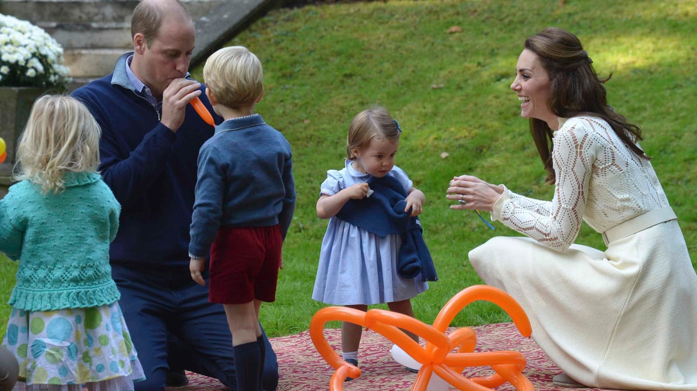 Nun legt Papa William selbst Hand und Mund an die Ballons an. Kate freut sich, Georg schaut interessiert zu.