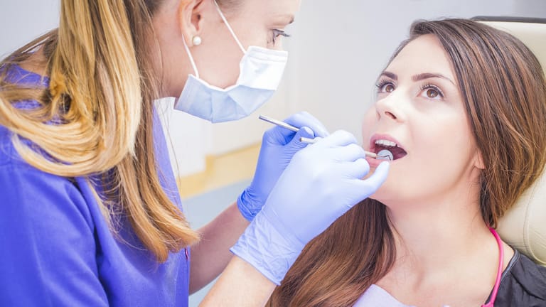 Zahnärztin reinigt Zähne einer Patientin