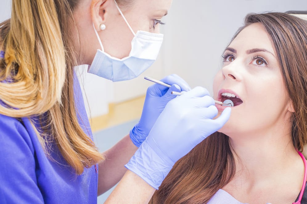 Zahnärztin reinigt Zähne einer Patientin