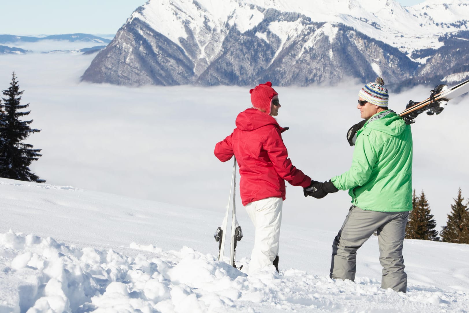 Couple Admiring Mountain View Whilst On Ski Holiday In Mountains