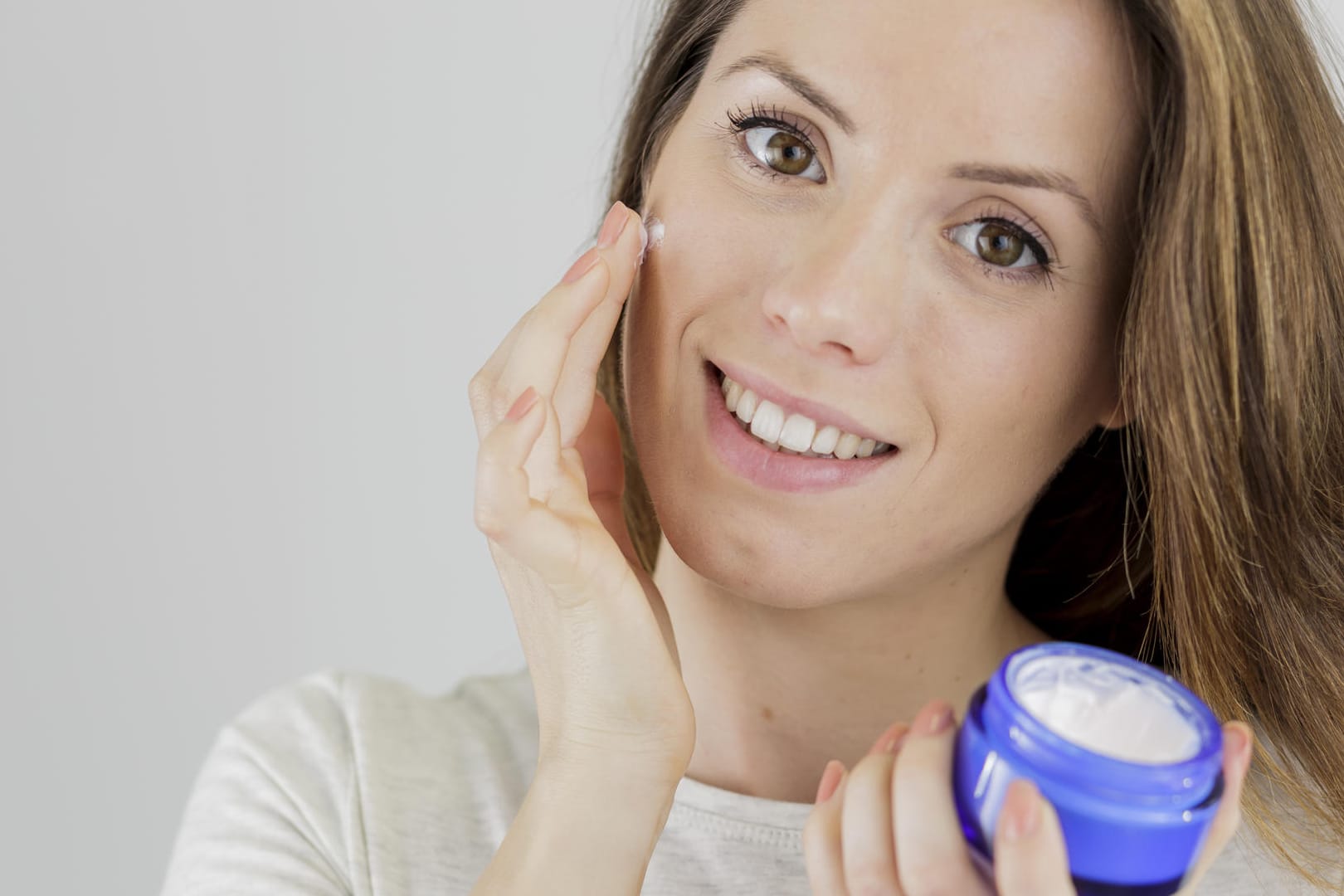 Eine Frau mit einer Creme: Tagescremes enthalten meist Antioxidantien, die die Haut schützen.