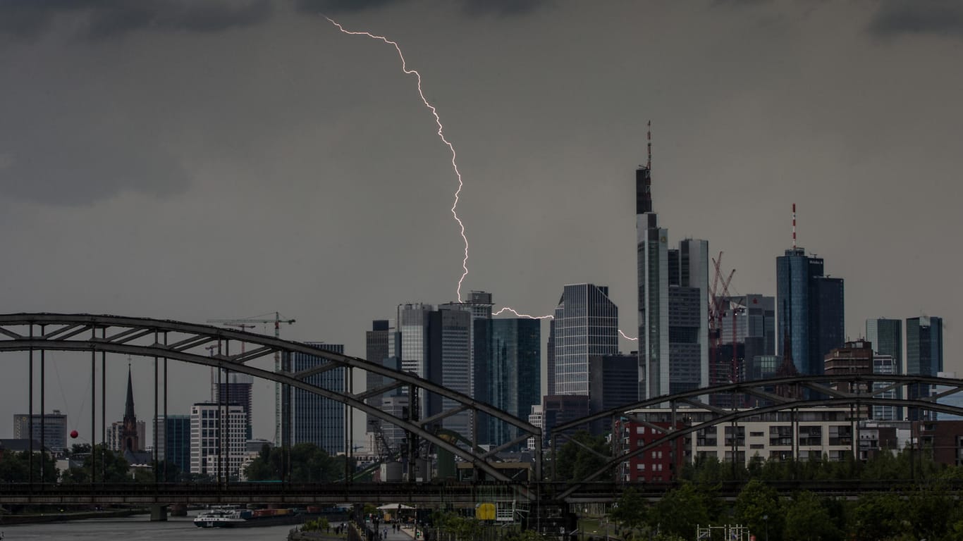 Ein Blitz durchzuckt den Abendhimmel während eines Gewitters über den Frankfurter Bankentürmen: Wegen der Gewitter stockte die Abfertigung am Frankfurter Flughafen.