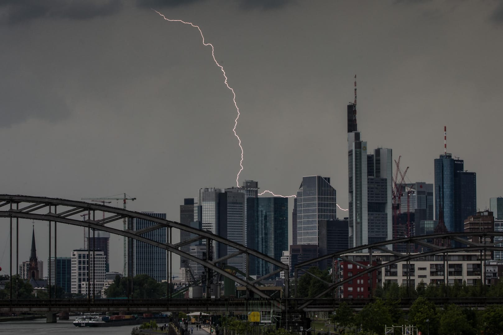 Ein Blitz durchzuckt den Abendhimmel während eines Gewitters über den Frankfurter Bankentürmen: Wegen der Gewitter stockte die Abfertigung am Frankfurter Flughafen.