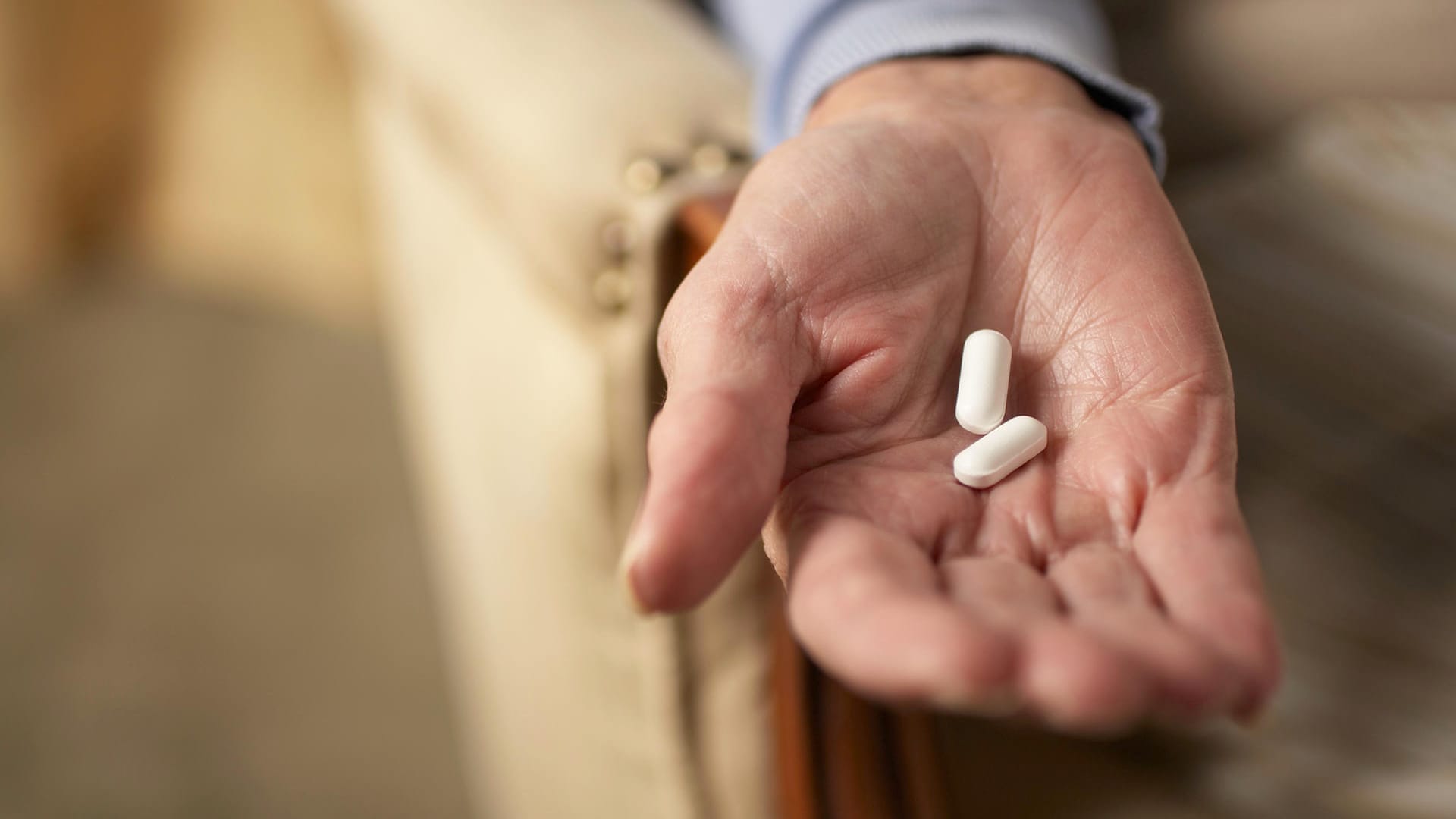 Hand einer alten Frau mit Tabletten