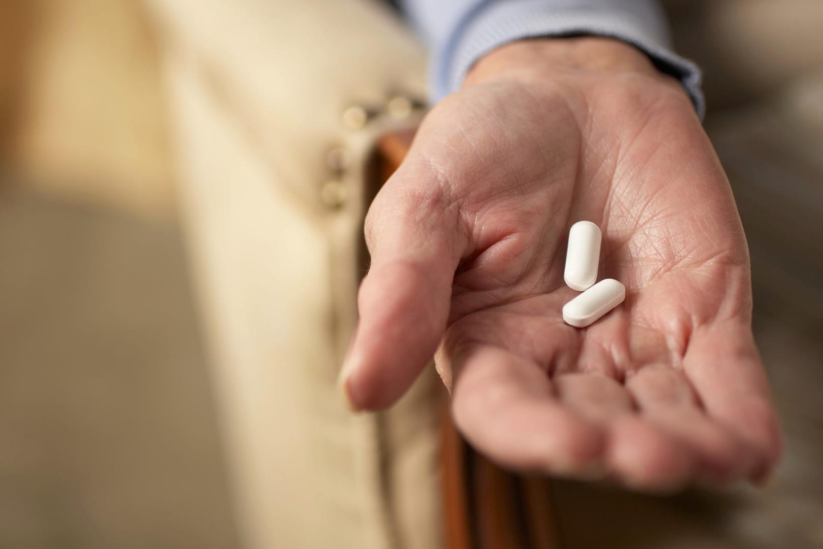 Hand einer alten Frau mit Tabletten