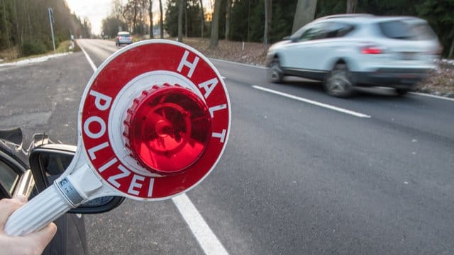 Ein Polizist hält eine Polizeikelle. Ein Polizist hält eine Polizeikelle.