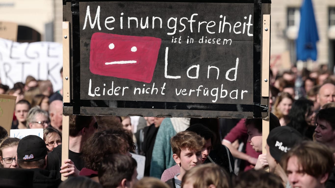 Demonstranten in Leipzig halten ein Schild mit der Aufschrift: ""Meinungsfreiheit ist in diesem Land leider nicht verfügbar" hoch.