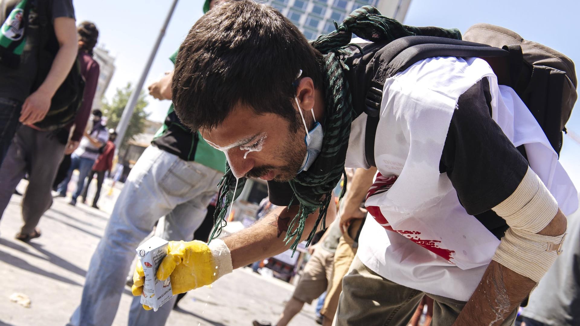 Ein Demonstrant versucht sich mit Milch das Tränengas aus den Augen zu waschen.