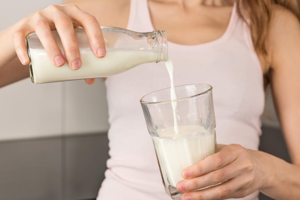 Frau gießt sich ein Glas Milch ein: Zahlreiche Studien untersuchen den Zusammenhang zwischen dem Verzehr von Milch oder Milchprodukten und dem Risiko für Osteoporose.
