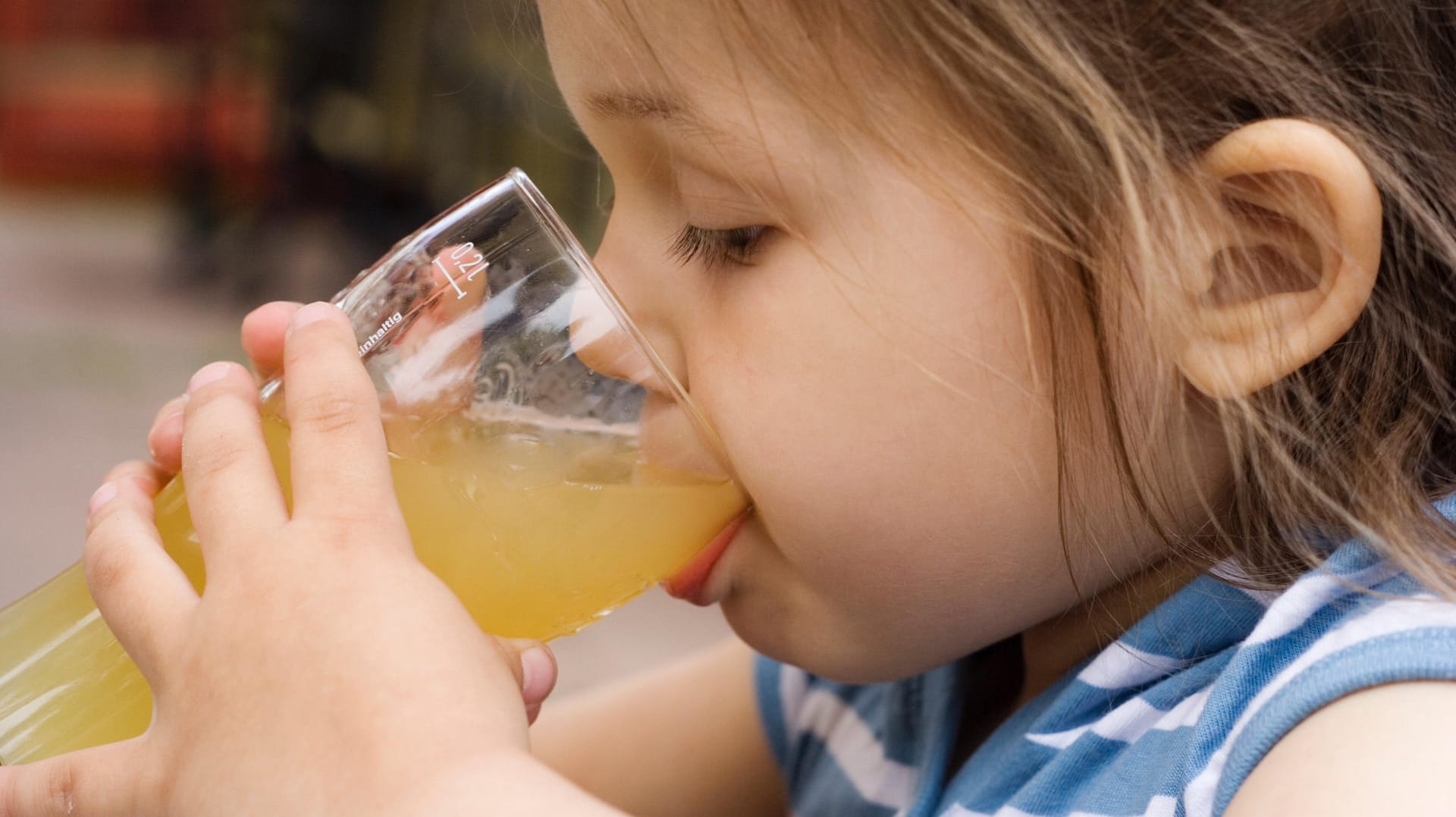 Mädchen trinkt Saft: Aufgewärmt können bestimmte Fruchtsäfte Beschwerden lindern.