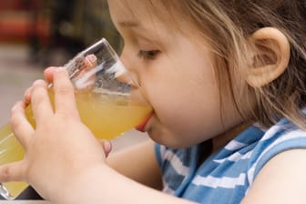 Mädchen trinkt Saft: Aufgewärmt können bestimmte Fruchtsäfte Beschwerden lindern.