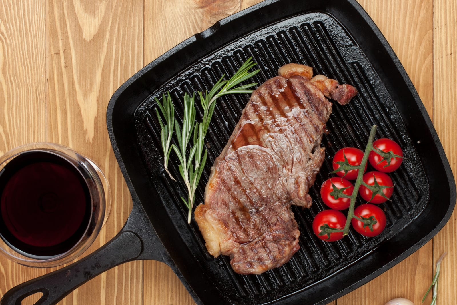 Sirloin steak with rosemary and cherry tomatoes on frying pan