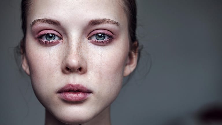 Eine junge Frau weint: Menschen mit Depressionen ziehen sich oft zurück und wirken wie versteinert.