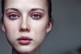 Eine junge Frau weint: Menschen mit Depressionen ziehen sich oft zurück und wirken wie versteinert.