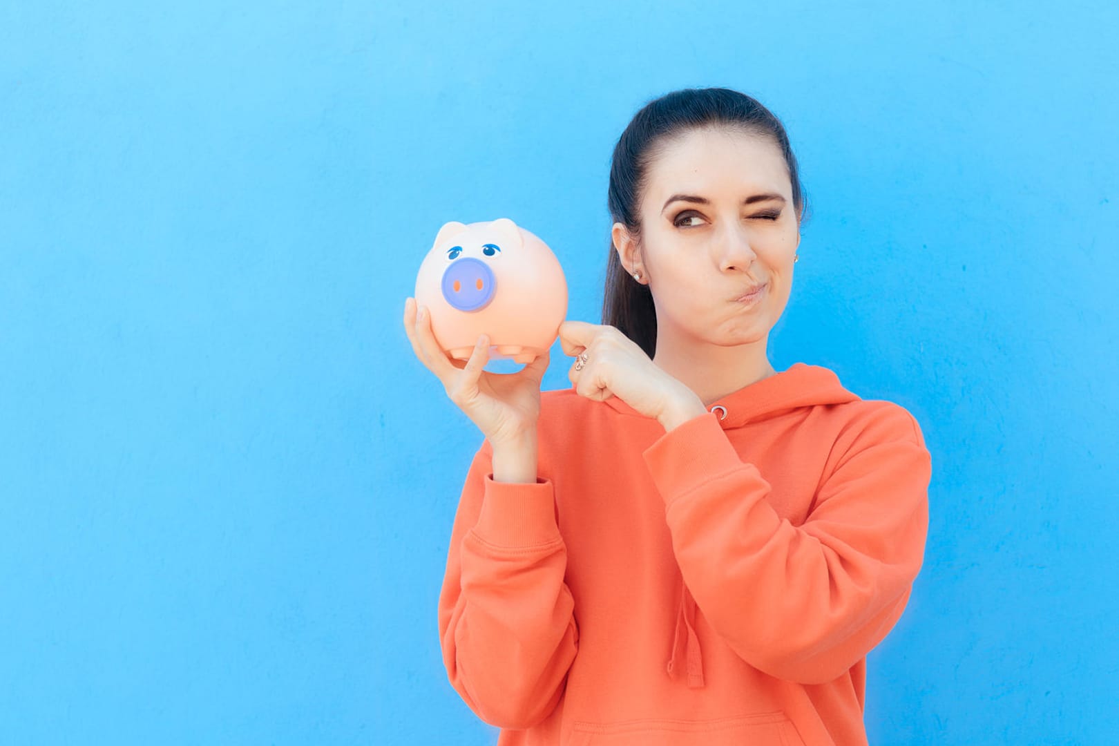 Eine junge Frau checkt ihr Sparschwein (Symbolbild): Gerade weil Frauen im Schnitt weniger Geld verdienen, sollten sie sich umso mehr mit ihren Finanzen beschäftigen.