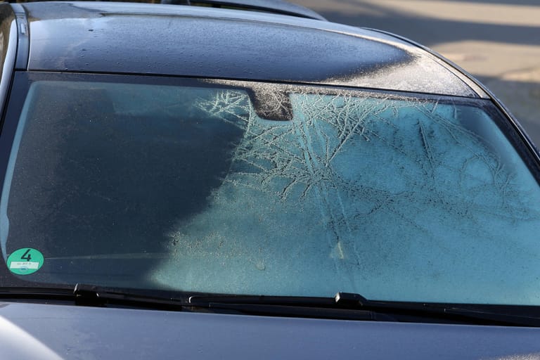 Ein eiskalter Morgen, ein Auto ist in Siegen zugefroren, die Sonne hat schon einen Teil vom Eis aufgetaut Fruehling im S