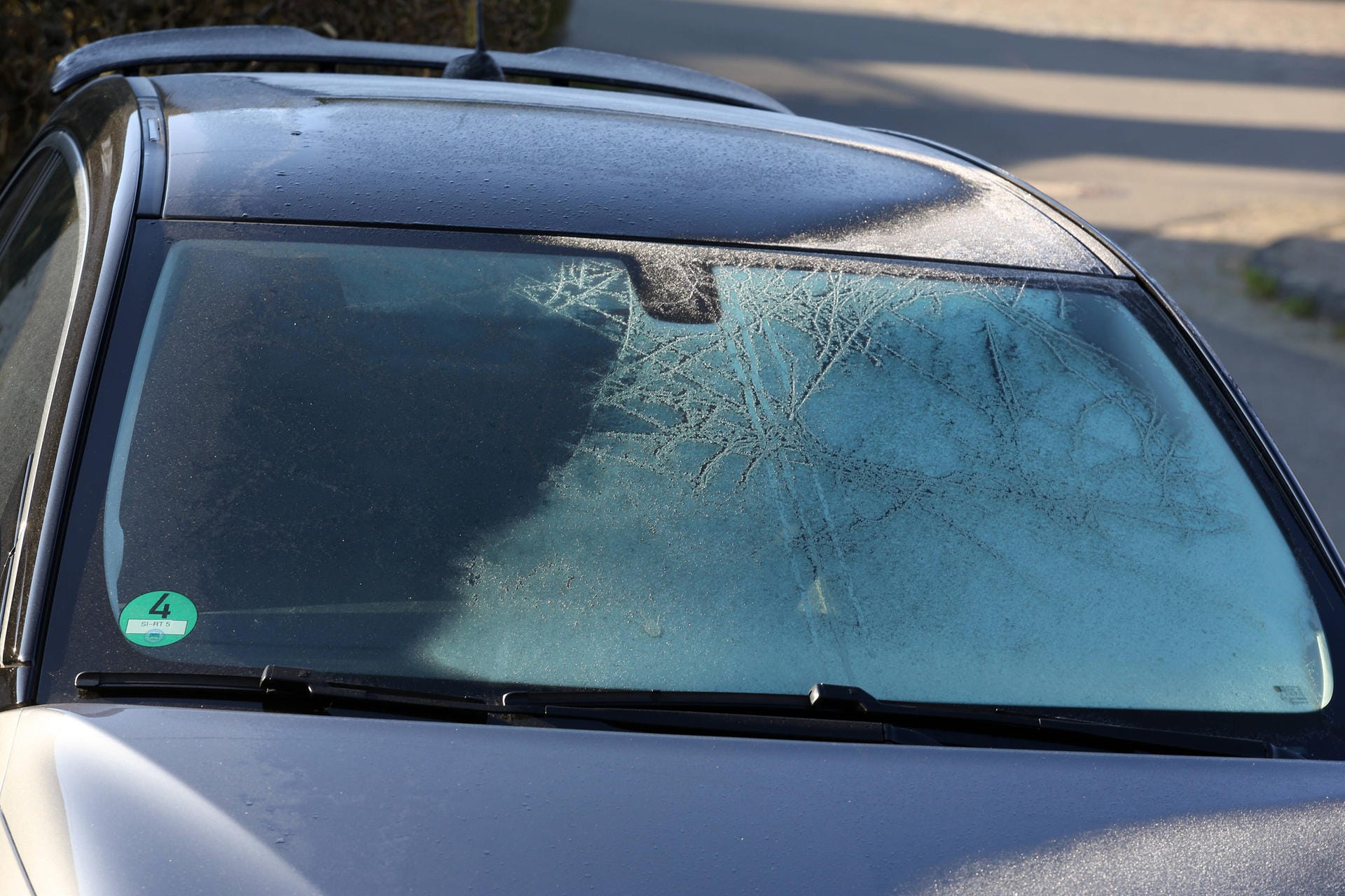 Ein eiskalter Morgen, ein Auto ist in Siegen zugefroren, die Sonne hat schon einen Teil vom Eis aufgetaut Fruehling im S