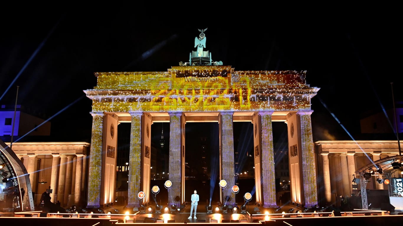 Artists stand on stage after fireworks exploded over Berlin's landmark Brandenburg Gate to usher in the new year during a concert 'Willkommen 2021' (Welcome 2021)