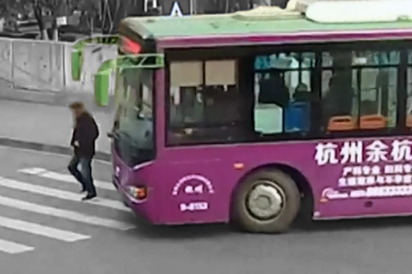 Busunglück in China: Ein Mann kommt unter die Räder und Passanten eilen zu Hilfe.