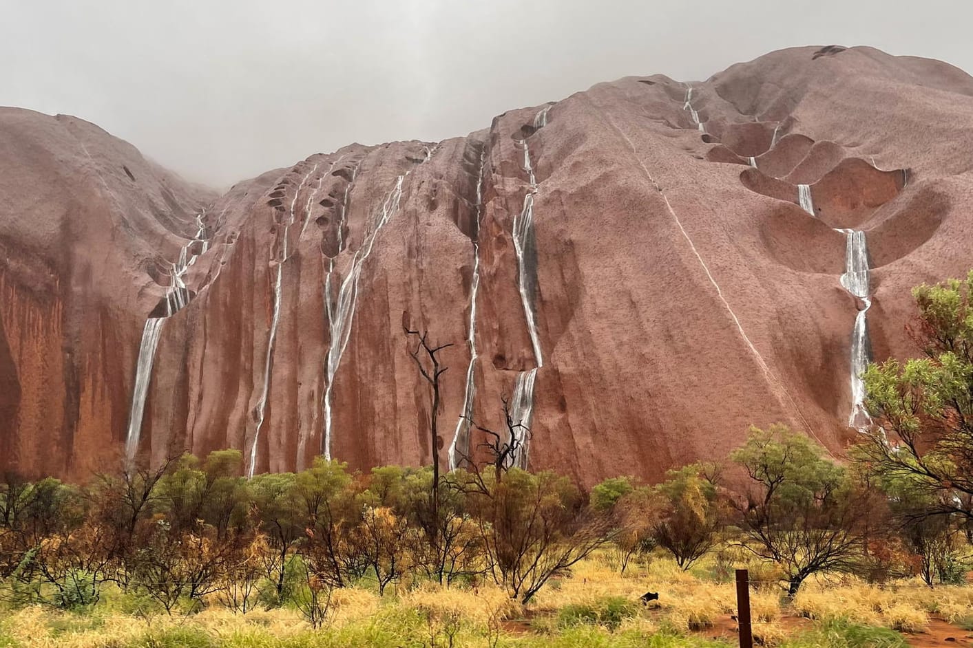 Waterfalls tumble over the surface of Uluru in the Northern Territory, Australia