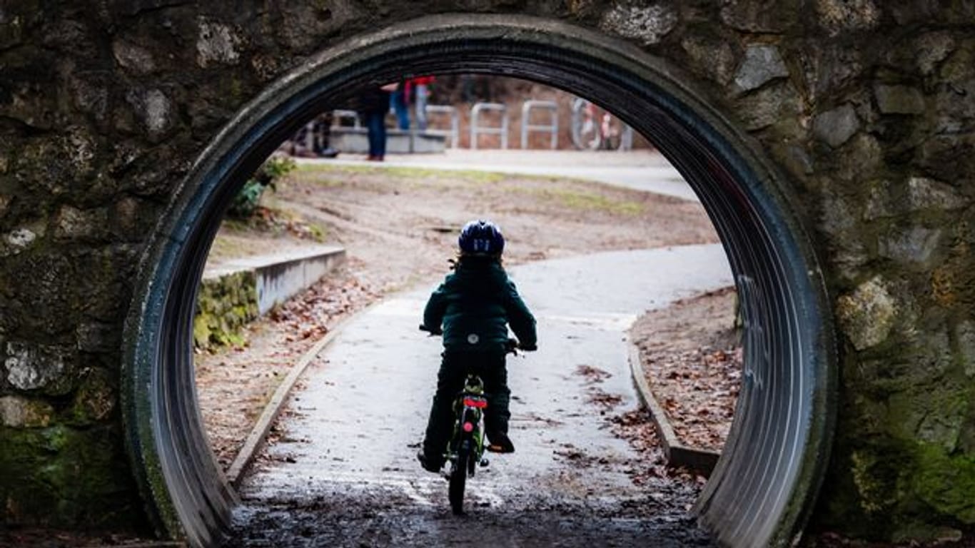 Ein Kind radelt durch einen Tunnel in einem Park in Berlin.