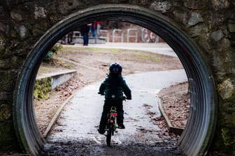 Ein Kind radelt durch einen Tunnel in einem Park in Berlin.