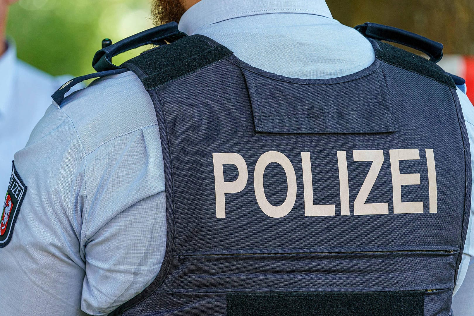 "Polizei" steht auf der Weste eines Beamten (Symbolbild): Bei den Durchsuchungen ging es um Verstöße gegen die Lebensmittelhygiene-Verordnung.
