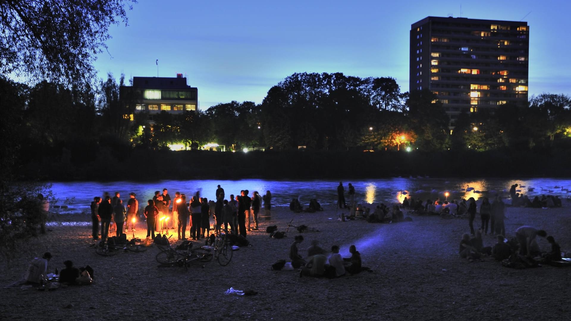 Menschen feiern an der Isar in München (Archivbild): Die Stadt sucht Orte für Partys draußen.